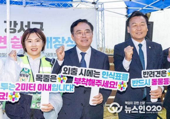 진교훈 서울 강서구청장(가운데)이 황금내근린공원에 조성된 반려견 쉼터 개장식에서 반려견 산책 시 유의사항 문구가 적힌 손팻말을 들어보이고 있다.